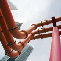 pipes carrying water through a city with office blocks in the background