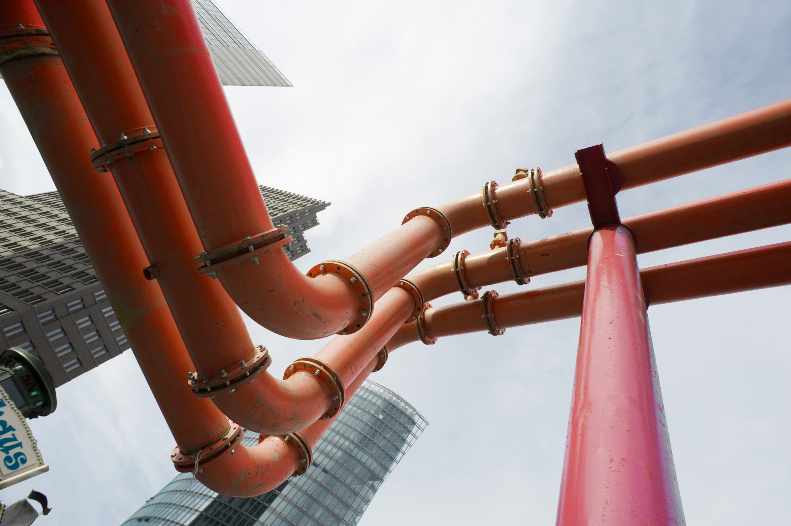 pipes carrying water through a city with office blocks in the background